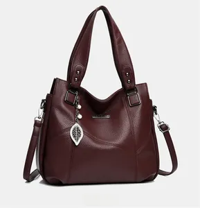 Détail d'un sac cabas bordeaux en cuir PU avec pendentif perle et texture grainée fine