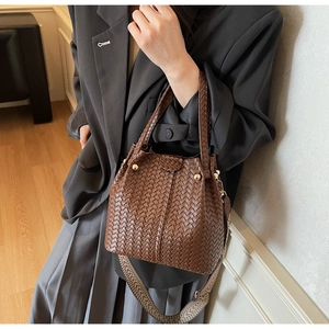 Detail of brown woven tote bag with metallic studs and geometric patterned shoulder strap
