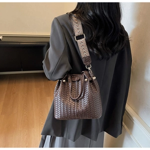 Detail of dark brown woven leather bucket bag with ethnic patterned wide shoulder strap