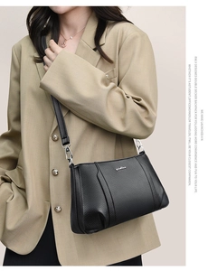 Detail of black lychee grain leather crossbody bag with silver hardware and logo