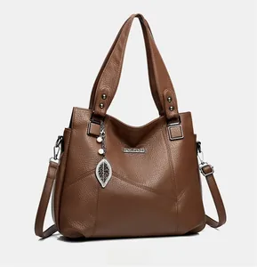 Détail du sac à main en cuir litchi marron foncé avec pendentif de feuille et perle