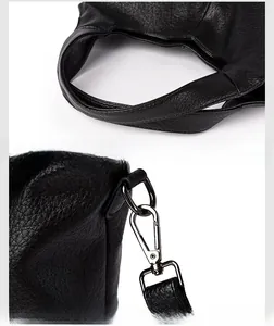 Detail of comfortable handle and dark metal hardware buckle on black lychee leather bag