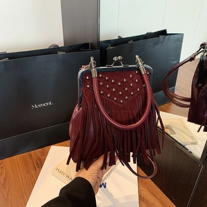 Detail of burgundy tassel handbag with silver rivets and vintage metal clasp design
