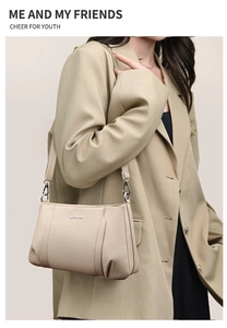 Detail of beige lychee grain leather crossbody bag with metal logo and pleated sides