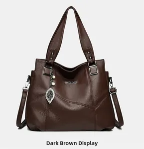 Vue détaillée du sac cabas marron foncé montrant le cuir grainé et le pendentif feuille