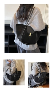 Detail of black suede tote bag featuring a prominent gold pillar lock and slim straps