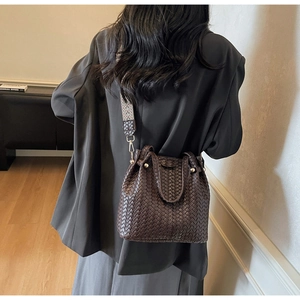 Detailed close-up of dark brown woven texture and gold metal studs on a bucket bag