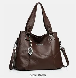 Détail du sac à main en cuir marron avec grain de litchi et pendentif de feuille en perle