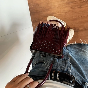 Top view of deep burgundy suede handbag featuring decorative tassels and silver studs