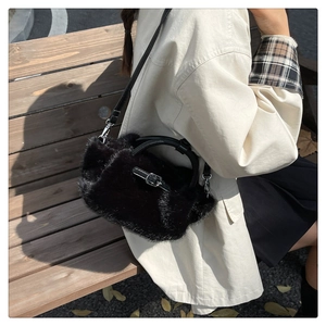 Detail der schwarzen flauschigen Plüschtasche mit Ledergriffen auf einer Holzbank