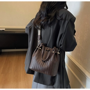 Detail of dark brown woven leather bucket bag with vintage patterned fabric shoulder strap