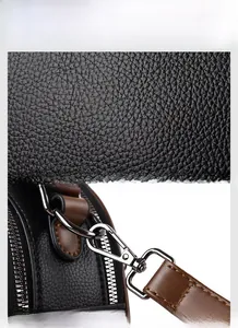 Detail of black lychee grain leather handbag with brown strap and silver metal hardware