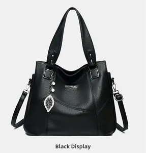 Détail du cabas en cuir grainé noir avec un pendentif décoratif en forme de feuille