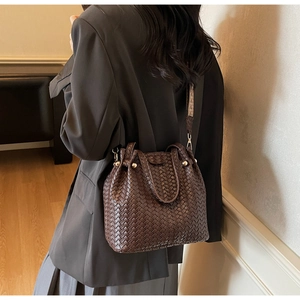 Close-up of dark brown woven texture bucket bag with gold hardware and jacquard strap