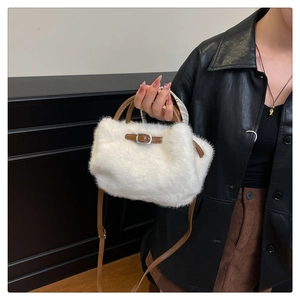 Detail einer weißen Plüschtasche mit braunen Ledergriffen und verstellbarem Gurt