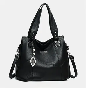 Détail du sac cabas en cuir noir grainé avec pendentif en perle et feuille évidée