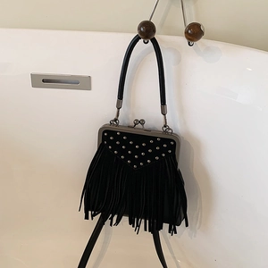 Detail of black fringe handbag with silver studs and retro metal clasp closure