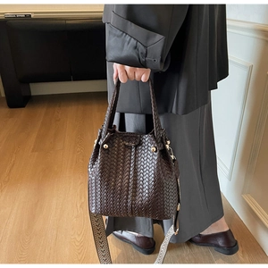 Detail of vintage woven bucket bag with brown texture and geometric embroidered strap