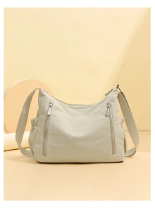 Detail view of beige nylon crossbody bag with vertical zippers and drawstring side pockets