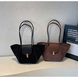 Detail of suede tote bags in black and brown with gold buckles and chic wing design