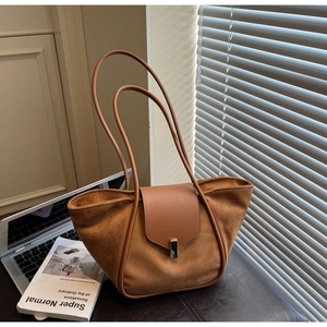 Detail of caramel tote bag with suede texture and gold buckle in a modern office setting