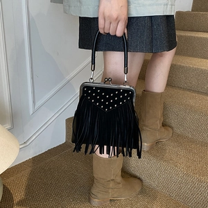 Macro detail of black tassel handbag with silver rivet studs and vintage metal clasp