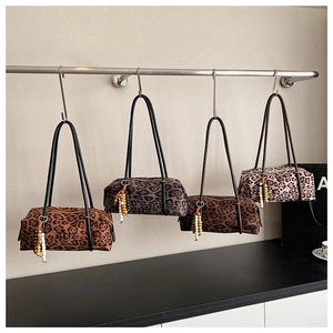 Detail of leopard print cylinder handbags featuring beaded charms and long shoulder straps
