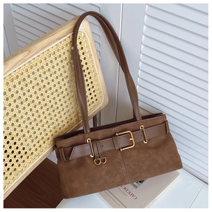 Détail du sac sous l'aisselle en daim marron avec boucle en métal sur chaise tressée