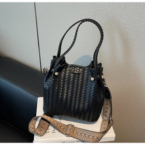 Detail of black woven bucket bag showing textured pattern and ethnic style strap