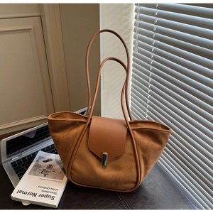 Detailed macro view of the brown suede tote bag with golden twist lock on a desk