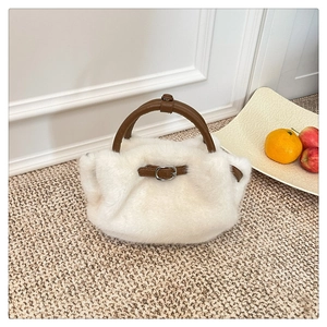 Detail einer weißen flauschigen Handtasche mit dunkelbraunem Ledergriff auf Teppich