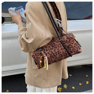 Detail of leopard print cylinder bag with colorful bead charm and long black strap