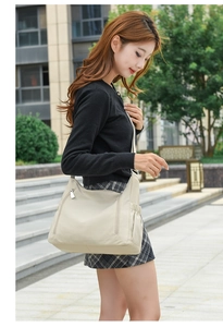 Side view of a large cream oxford fabric crossbody bag with drawstring side pocket