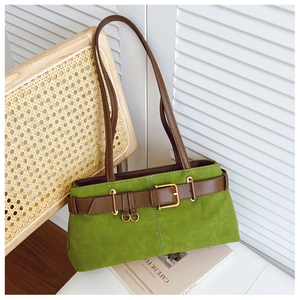 Détail du sac sous les bras en daim vert avec boucle décorative en cuir marron sur le devant