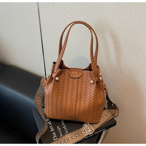 Detail of woven bucket bag in caramel brown featuring an ethnic printed wide shoulder strap