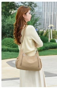 Close-up of khaki nylon shoulder bag featuring multiple functional zipper pockets