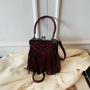Detail of burgundy tassel handbag with silver rivets and vintage metal clasp closure