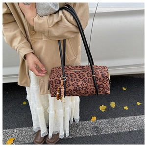 Detail of leopard print cylinder bag with decorative beads on a textured surface
