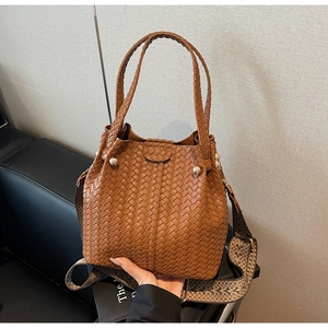 Close-up of brown woven bucket bag featuring an ethnic style jacquard wide shoulder strap