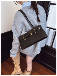 Détail du sac sous le bras en daim noir avec boucles dorées et sangle en cuir