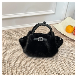 Detail der flauschigen schwarzen Plüsch-Handtasche mit Lederschnalle und Rundgriff
