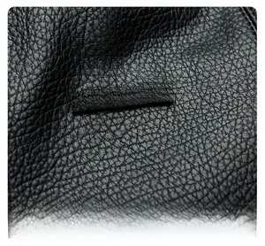 Détail du cuir grainé noir avec une plaque logo métallique argentée rectangulaire