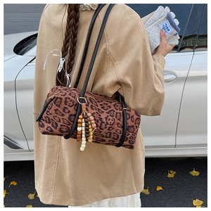 Detail of leopard print cylinder bag with beaded tassel charm and autumn street background