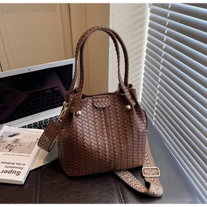Detail of woven brown bucket bag with colorful ethnic strap on a modern office desk