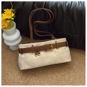 Détail du sac sous le bras en daim blanc cassé avec une boucle de ceinture marron foncé