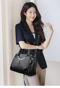 Détail du sac à main noir en cuir grainé avec boucle en métal argenté sur le mannequin