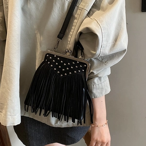 Detail of bohemian black crossbody bag with silver rivets and long tassel on a model