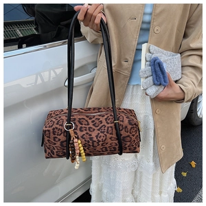 Detailed view of leopard print cylinder handbag with beaded tassel and zipper closure