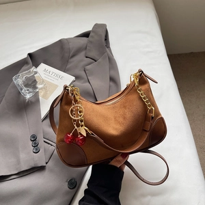 Vintage caramel suede underarm bag with gold chain and cherry charm on grey blazer