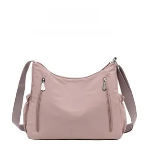 Front view of dusty pink oxford fabric crossbody bag with vertical zippers and side pockets